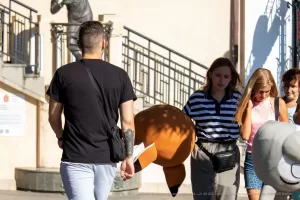 Фотография мужчины с татуировкой на руке, идущего рядом с двумя девушками. Виден фрагмент татуировки с изображением лисы.