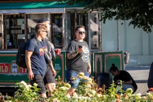 Фото тату: женщина с татуировкой в виде черепа с розой на руке стоит у киоска с едой вместе с мужчиной.