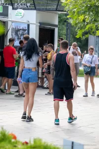 Фото тату на пояснице девушки, идущей по улице. Видна татуировка в виде узора, выполненная в черных тонах.