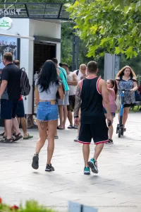 Фото тату на пояснице девушки, идущей по улице. Видна татуировка в виде узора, выполненная в черных тонах.