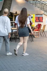 Фото татуировок на теле: небольшие цветки на плече, надпись на руке и цветок на ноге, выполненные в ярких цветах.