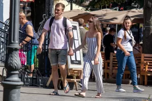 Фотография молодого человека с татуировкой на предплечье, идущего с девушкой по улице. Татуировка выполнена в черном цвете и представляет собой геометрический узор.