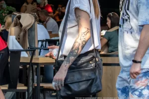Фото татуировки в виде рукава на руке девушки, выполненное в стиле blackwork с использованием черных чернил. Видны сложные узоры и детализированные элементы рисунка.