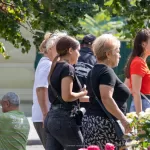 Фото тату на шее: арабская каллиграфия, выполненная черными чернилами. Татуировка расположена сзади, под волосами, создавая элегантный и загадочный образ. Женщина в толпе.