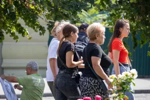 Фото тату на шее: арабская каллиграфия, выполненная черными чернилами. Татуировка расположена сзади, под волосами, создавая элегантный и загадочный образ. Женщина в толпе.