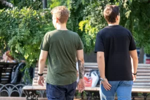 Фото тату: два мужчины идут по улице, у одного из них на плече видна татуировка в виде черного дракона.