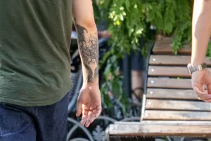 Фото татуировки дракона на руке мужчины. Рисунок татуировки выполнен в черном цвете и имеет детализированный вид.