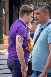 Фото тату котенка с веточками на плече. Черно-белый рисунок татуировки в реалистичном стиле, выполненный с высокой детализацией.