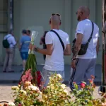 Фото тату на спине мужчины, держащего букет цветов. Рисунок татуировки выполнен в черных тонах, детализированный и реалистичный.
