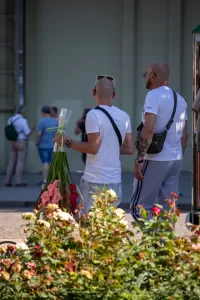 Фото тату на спине мужчины, держащего букет цветов. Рисунок татуировки выполнен в черных тонах, детализированный и реалистичный.