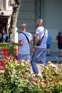 Фотография двух мужчин с татуировками на предплечьях, держащих букеты цветов. Тату выполнены в черном цвете, с преобладанием геометрических и абстрактных мотивов.