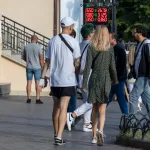Фото татуировки на руке мужчины: детализированный рисунок в темных тонах, выполненный на предплечье. Изображение сделано на улице, в городской среде.
