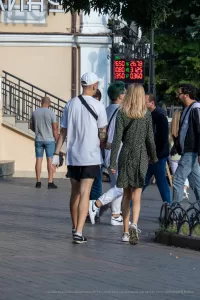 Фото татуировки на руке мужчины: детализированный рисунок в темных тонах, выполненный на предплечье. Изображение сделано на улице, в городской среде.