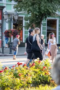 Фото тату: мужчина с татуировкой на предплечье, изображающей череп, цветы и другие элементы в стиле реализм.