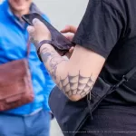 Тату красная снежинка на лице и наручники с паутиной на руке молодой девушки - Уличная тату (street tattoo) № 14–210821 3