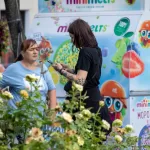 Фото тату на руках девушки, стоящей возле фудтрака с мороженым. Черно-белые татуировки в стиле графика, с детализированными узорами.