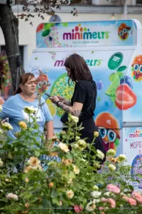 Фото тату на руках девушки, стоящей возле фудтрака с мороженым. Черно-белые татуировки в стиле графика, с детализированными узорами.
