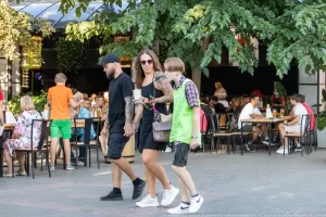 Фотография семьи, идущей по улице. У матери на руке видны татуировки с цветочными мотивами, а у отца - на руках.