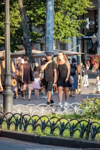 Фотография пары, идущей по улице. У женщины на руке заметны татуировки с цветочными мотивами, а у мужчины - на руках.