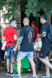 Фотография мужчины с татуировкой на руке и надписью "Sullen" на спине, сделанная на улице. Видны детализированные рисунки в темных тонах.