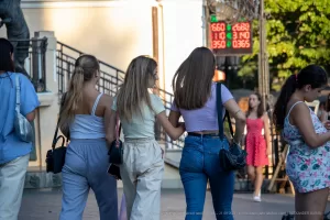 Фотография группы девушек, идущих по улице. У одной из девушек на руке видна небольшая татуировка.