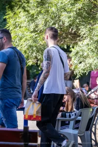 Фото тату на плече и руке мужчины, выполненное в стиле реализм с использованием черных чернил. Видны детализированные узоры и тени.