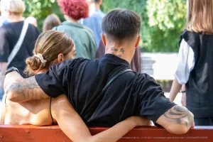 Фотография пары в объятиях, у мужчины татуировки на руке и шее, у женщины - на спине. Идеально для поиска идей для парных тату.