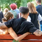 Фотография пары в объятиях, у мужчины татуировки на руке и шее, у женщины - на спине. Идеально для поиска идей для парных тату.