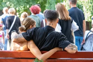 Фотография пары в объятиях, у мужчины татуировки на руке и шее, у женщины - на спине. Идеально для поиска идей для парных тату.