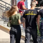 Фото тату на руке девушки: небольшой рисунок цветка в черном цвете, расположенный на запястье.