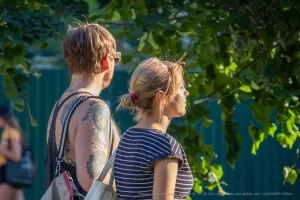 Фото тату на плече мужчины: реалистичный портрет женщины в черно-серых тонах, абстрактные элементы, уличная фотография, вид сбоку.