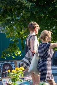 Фото тату на плече мужчины: реалистичный портрет женщины в черно-серых тонах, абстрактные элементы, уличная фотография, вид сбоку.