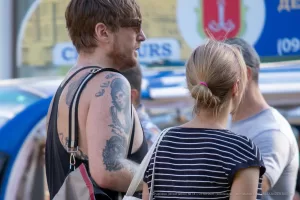 Фото тату на плече мужчины: крупный план реалистичного портрета в черно-серых тонах, детализированный рисунок, уличная фотография.