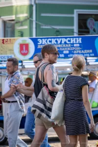 Фото тату на плече мужчины: черно-серая татуировка с портретом и абстрактными элементами, детализированный рисунок, уличная фотография.