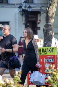 Фото тату на руке девушки, идущей по улице. Рисунок татуировки выполнен в стиле реализм, изображает портрет женщины.