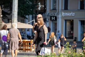 Фото тату на руке девушки, идущей по улице. Рисунок татуировки выполнен в стиле реализм, изображает портрет женщины.