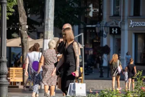 Фото тату на руке девушки, идущей по улице. Рисунок татуировки выполнен в стиле реализм, изображает портрет женщины.