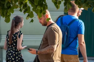 Фотография мужчины с татуировкой на руке, смотрящего в сторону. Татуировка выполнена в темных тонах и имеет сложный узор.