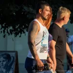 Фотография татуированного рукава на мужчине, сделанного в ярком и детализированном стиле. Мужчина идет по улице, и татуировка хорошо видна.