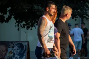 Фотография татуированного рукава на мужчине, сделанного в ярком и детализированном стиле. Мужчина идет по улице, и татуировка хорошо видна.