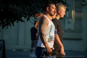 Фотография татуированного рукава на мужчине, сделанного в ярком и детализированном стиле. Мужчина идет по улице, и татуировка хорошо видна.