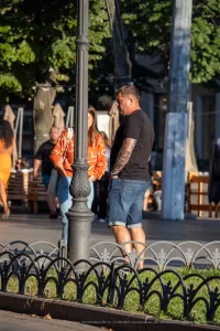 Фотография мужчины с татуировкой на предплечье, стоящего рядом с женщиной на городской улице. Татуировка выполнена в реалистичном стиле.