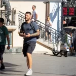 Фотография мужчины с татуировками на предплечьях, идущего по улице. Тату выполнены в черном цвете, с преобладанием геометрических и абстрактных мотивов.