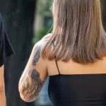 Фото тату медузы на плече девушки. Черно-белый рисунок татуировки с детально проработанными щупальцами и плавными линиями. Изящный эскиз тату.