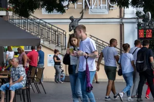Фотография мужчины с татуировкой на предплечье, идущего по улице. Татуировка выполнена в ярких цветах и изображает морского конька.