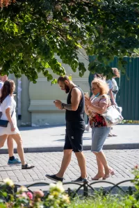 Фото тату на руке мужчины, идущего по улице. Видны детализированные черные чернила рисунка на коже.