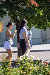 Фотография двух женщин, идущих по улице. У одной из них видна татуировка на руке.