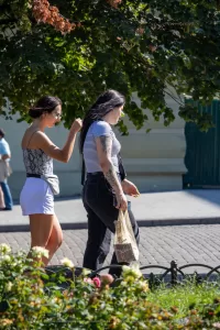 Фотография двух женщин, идущих по улице. У одной из них видна татуировка на руке.