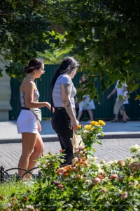 Фотография двух женщин, идущих по улице. У одной из них видна татуировка на руке.