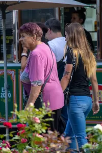 Фото двух женщин, одна из которых имеет татуировку на руке. Видна часть рисунка татуировки в виде темных линий. Уличная фотография тату.